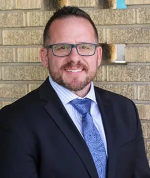 A man in a suit and tie standing next to a brick wall.