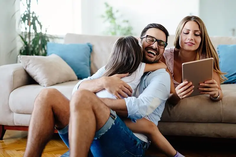 A man holding a girl while sitting on the couch